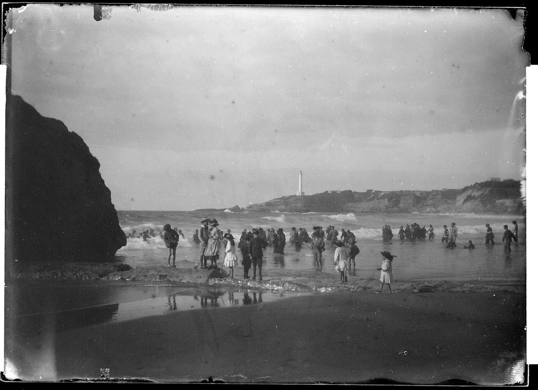 La grande plage de Biarritz à la fin du XIXe siècle : baigneurs dans les vagues, le phare de la pointe Saint-Martin au loin.